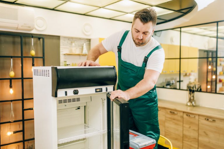 Worker with toolbox repair refrigerator at home All Area Appliance