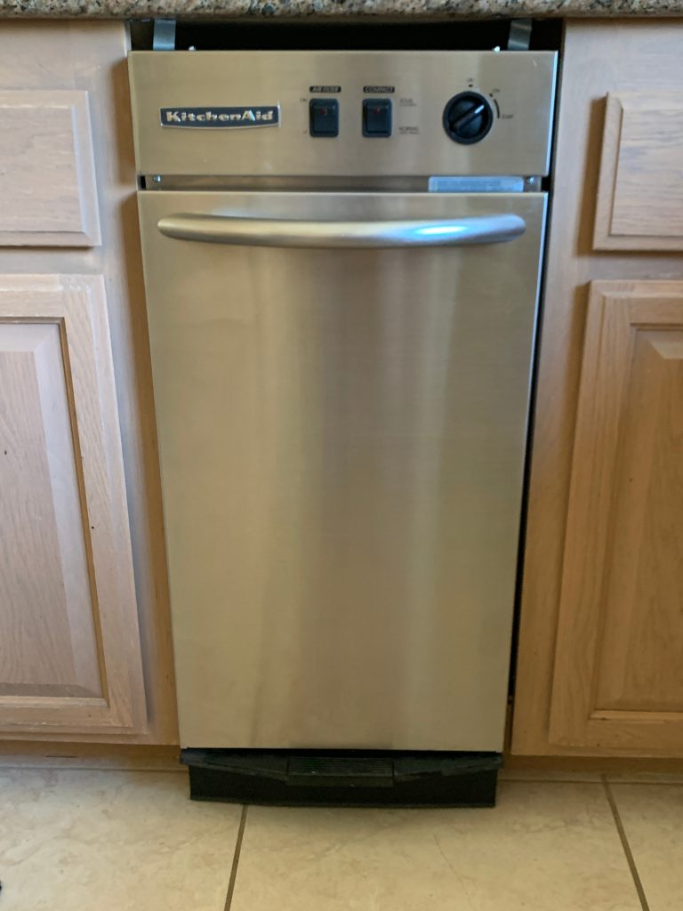 Close-up of a modern kitchen trash compactor, a common appliance that may require trash compactor repair when unusual sounds or issues occur.