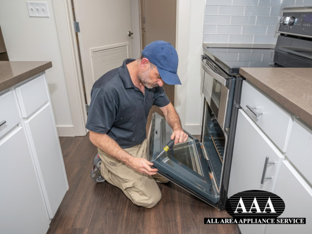 Appliance technician performing emergency appliance repair on a range oven, tightening screws to ensure safe and functional operation.